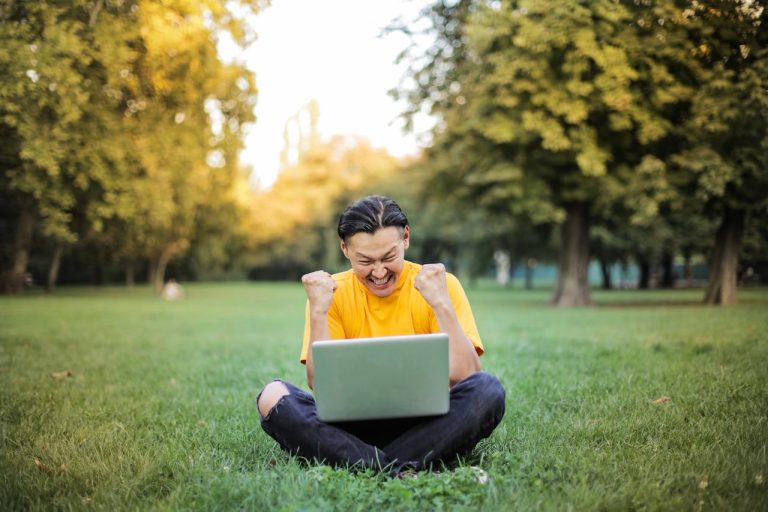 success man with laptop seated on grass